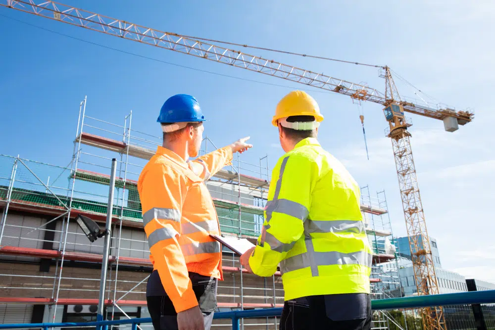Rear,View,Of,Two,Male,Architect,Wearing,Hardhat,Looking,At careers in construction